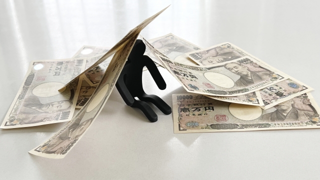 お金の上でうなだれる。豊明市で借金返済の相談は無料でできます